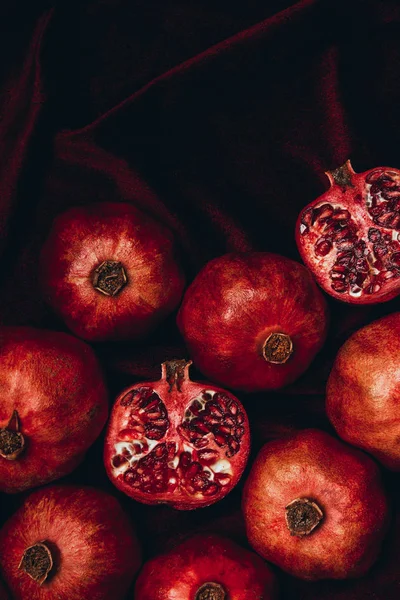 Vista superior de romãs dispostas em fundo de tecido de veludo vermelho — Fotografia de Stock