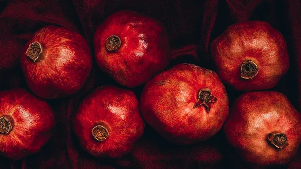 Flache Lage mit frischen Granatäpfeln auf rotem Samtstoff-Hintergrund — Stockfoto