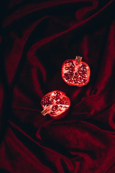 Верхний вид спелых половинки граната на красном бархатном фоне ткани — стоковое фото