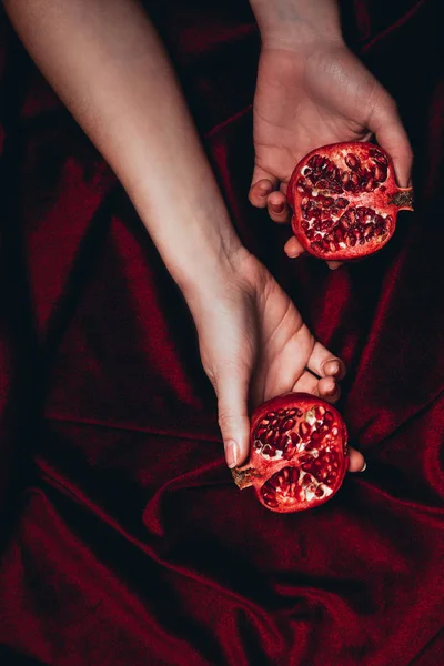 Abgeschnittene Aufnahme einer Frau mit reifen Granatapfelstücken auf rotem Velourstoff-Hintergrund — Stockfoto