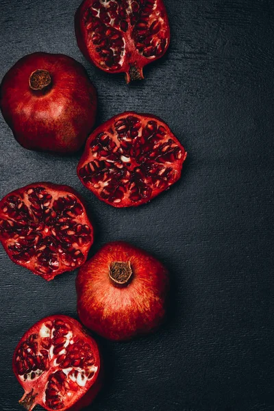 Top view of ripe pomegranates arrangement on black surface — Stock Photo