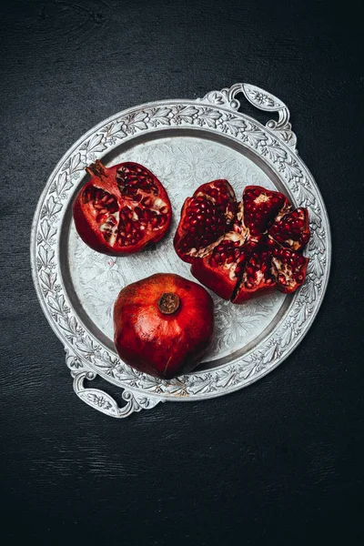 Flat lay com romãs frescas na bandeja de metal em mesa preta — Fotografia de Stock