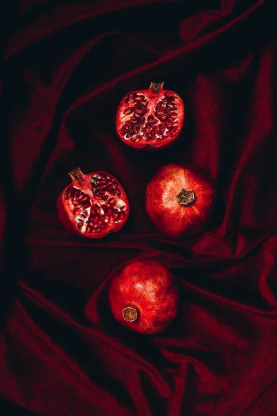 Vista superior de romãs maduras em pano de fundo de tecido de veludo vermelho — Fotografia de Stock