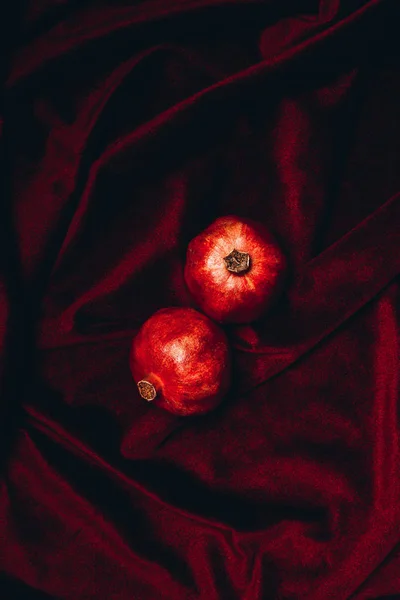 Top view of ripe pomegranates on red velvet fabric backdrop — Stock Photo
