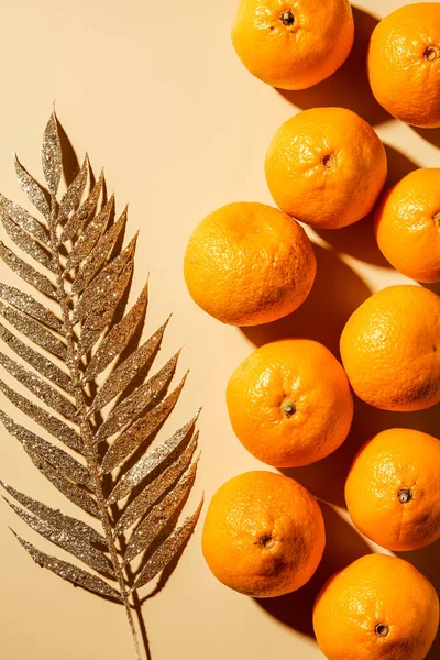 Vista dall'alto di mandarini e ramoscello d'oro decorativo su sfondo beige — Foto stock
