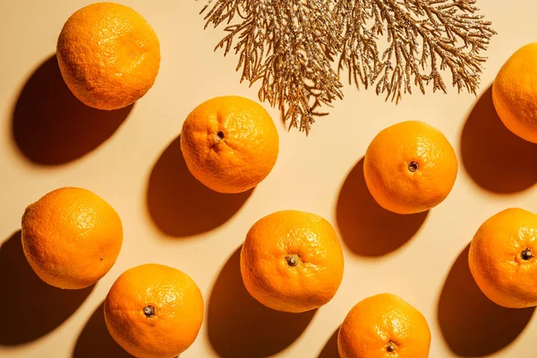 Flat lay with wholesome mandarins and decorative golden twig on beige background — Stock Photo