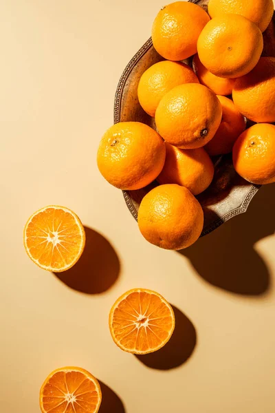 Flat lay with tangerines in metal bowl on beige backdrop — Stock Photo