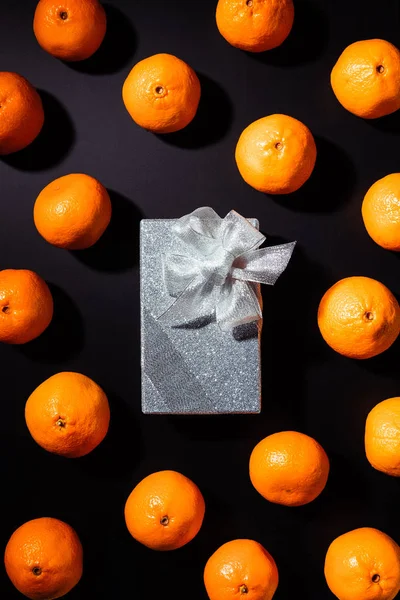 Vista superior de tangerinas frescas e caixa de presente de prata no fundo preto — Fotografia de Stock