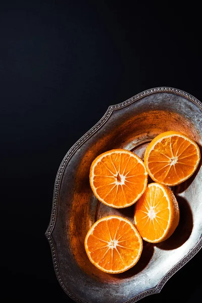 Vista superior de tangerinas e tigela de metal no fundo preto — Fotografia de Stock