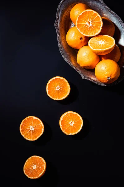 Flat lay with mandarins and metal bowl on black backdrop — Stock Photo