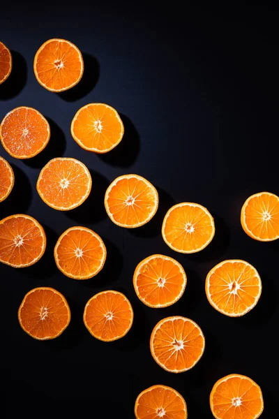 Cadre complet de mandarines coupées disposées moitiés sur fond noir — Photo de stock