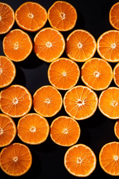 Quadro completo de tangerinas cortadas dispostas metades no fundo preto — Fotografia de Stock