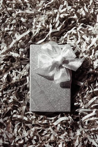 Top view of silver christmas gift on grey paper confetti backdrop — Stock Photo