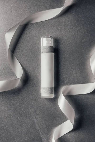 Elevated view of lotion between ribbons on silver — Stock Photo