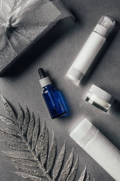 Plat laïc avec coffret cadeau, lotion, crème de beauté, sérum et ruban avec branche décorée sur argent — Photo de stock