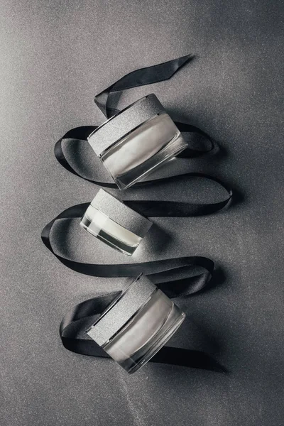 Draufsicht auf verschiedene Schönheitscremes mit schwarzem Band auf Silber — Stockfoto