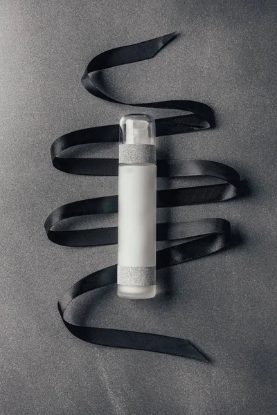 Flat lay with lotion and black ribbon on silver — Stock Photo