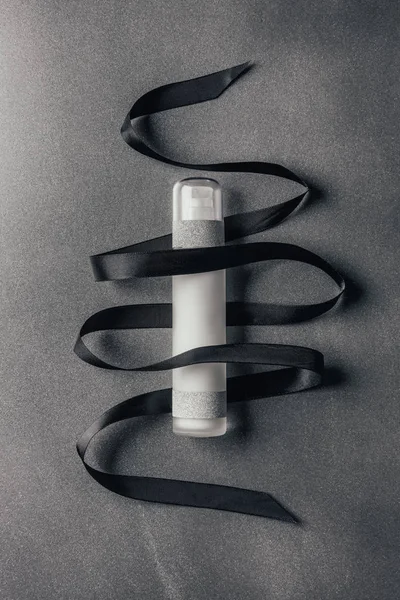 View from above of lotion and black ribbon on silver — Stock Photo