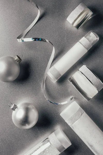 Top view of christmas balls, ribbon and beauty treatment equipment on silver — Stock Photo