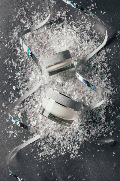 Elevated view of festive ribbons and beauty cream with decorated shavings on silver — Stock Photo