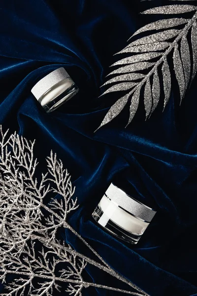 Vue de dessus de la crème de beauté entre les branches décorées d'argent sur la surface de velours — Photo de stock