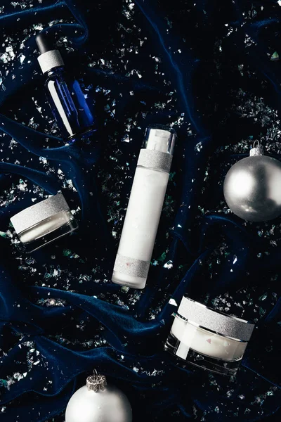 Flat lay with serum, beauty cream, lotion and silver christmas balls on velvet surface — Stock Photo