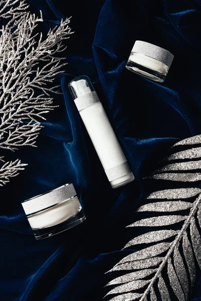 View from above of lotion and beauty cream between christmas silver branches on velvet surface — Stock Photo