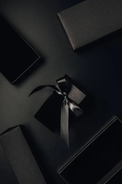 Вид зверху чорна пляшка парфумів з бантом і коробками на чорному — стокове фото