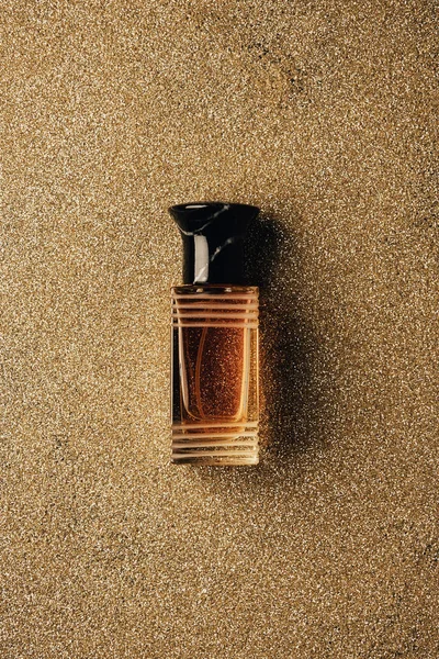 Vue du dessus du flacon de parfum sur fond doré scintillant — Photo de stock