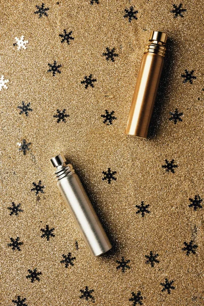 Vue de dessus des bouteilles de parfum dorées et argentées et des flocons de neige décoratifs — Photo de stock