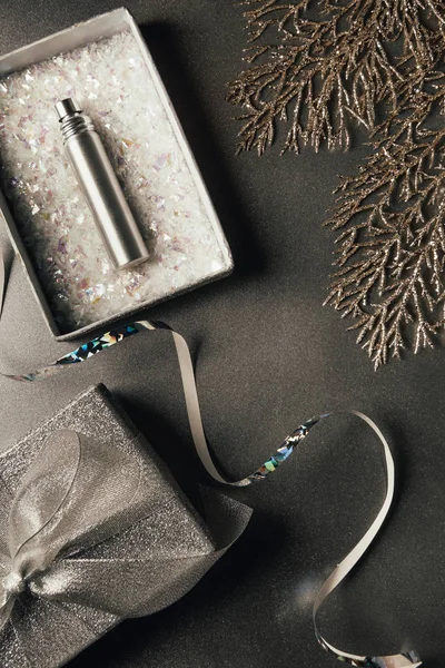 Vue du dessus du flacon de parfum en coffret cadeau, ruban argenté et brindilles brillantes décoratives sur gris — Photo de stock