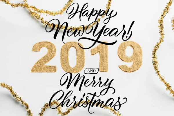 Top view of 2019 year sign made of golden glitters and garlands on white backdrop with 