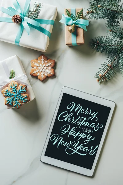 Vista superior de los regalos de Navidad, galletas de copo de nieve y tableta digital con letras de 