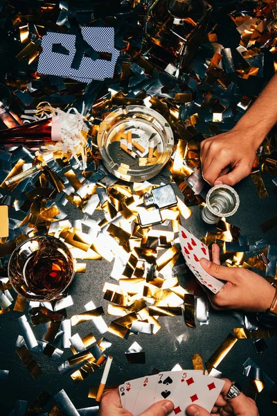 Cropped image of male friends playing poker at table covered by golden confetti — Stock Photo