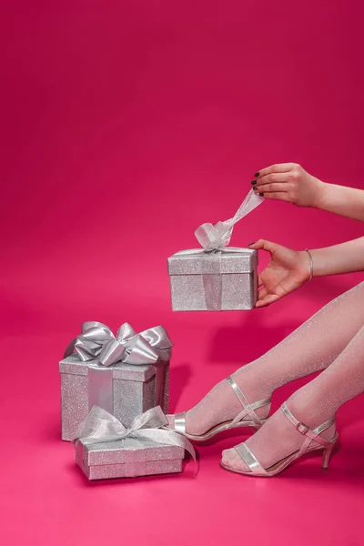 Cropped image of woman opening silver gift box at party on burgundy — Stock Photo