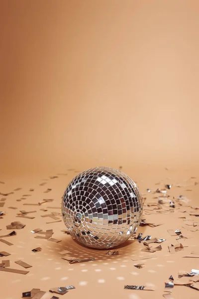 Shiny silver disco ball and confetti on beige — Stock Photo