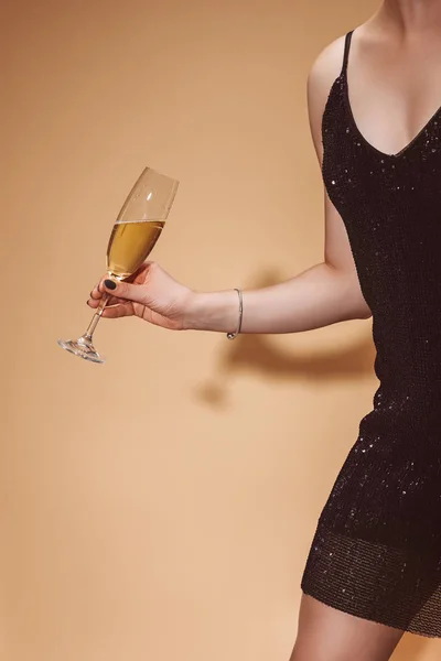 Cropped image of woman holding glass of champagne at party on beige — Stock Photo