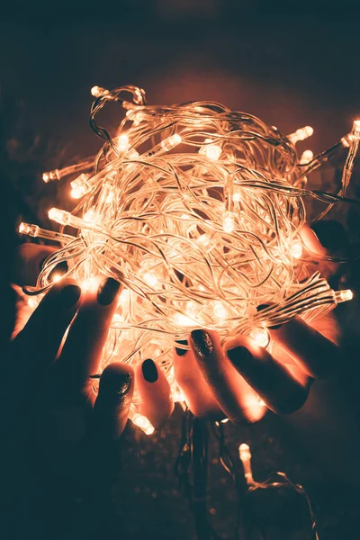 Plan recadré de la femme tenant des lumières festives lumineuses dans les mains — Photo de stock