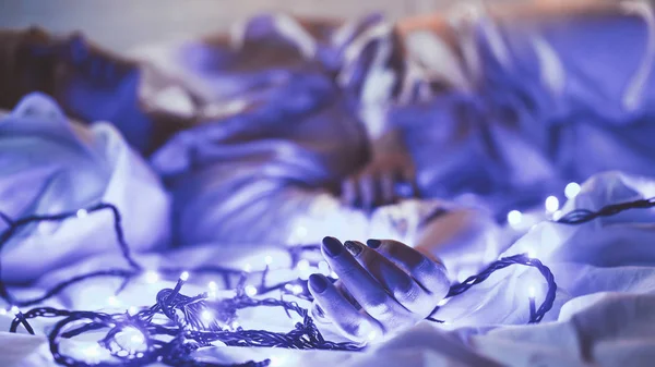 Selective focus of woman lying on bed with christmas festive lights — Stock Photo