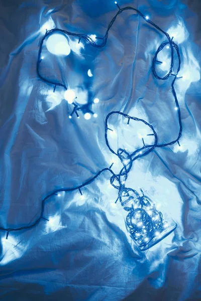 Top view of christmas festive lights and glass jar on bed — Stock Photo