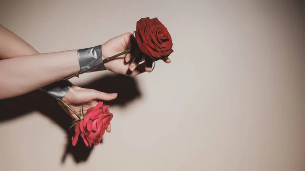 Частичный вид женщины с заклеенными красными розами цветами на бежевом фоне — стоковое фото