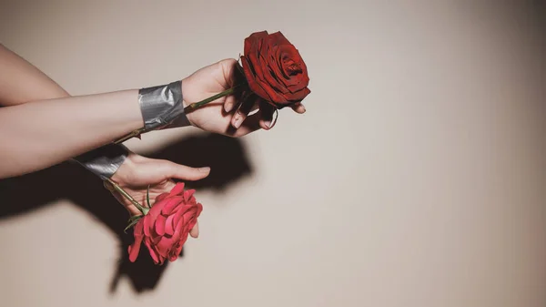 Partial view of woman with taped red roses flowers on beige background — Stock Photo