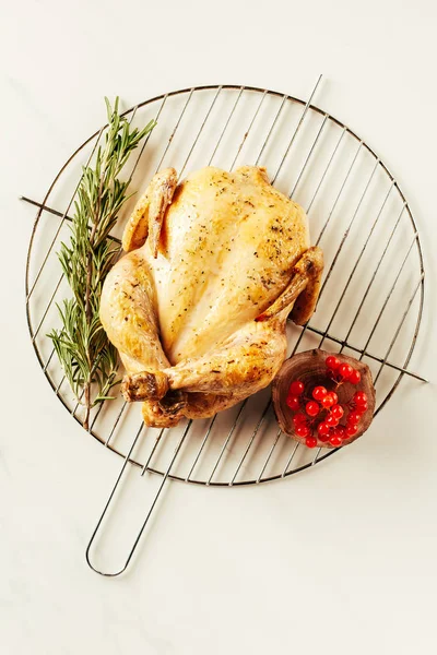 Top view of fried chicken, rosemary and berries on metal grille — Stock Photo