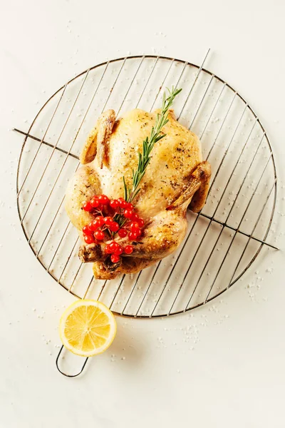 Top view of fried chicken, rosemary and berries on metal grille with lemon — Stock Photo