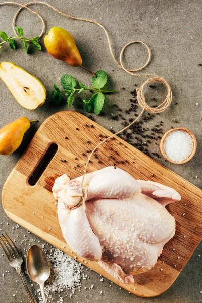 Vue du dessus du poulet cru sur planche à découper avec poires et verdure — Photo de stock