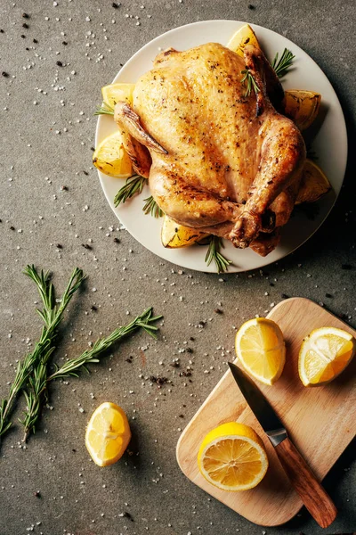 Top view of fried chicken on plate and cutting board with lemons and knife — Stock Photo