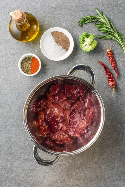 Top view of raw meat in pot, spices, oil, peppers, broccoli and rosemary — Stock Photo
