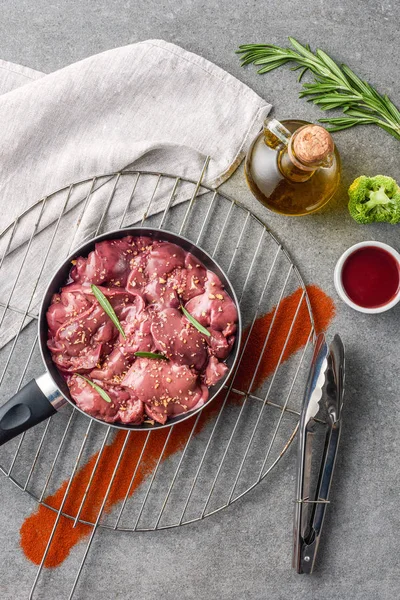 Carne cruda in padella su griglia metallica con olio, broccoli e salsa — Foto stock