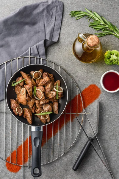 Top view of fried meat in fried pan on metal grille with oil, broccoli and sauce — Stock Photo