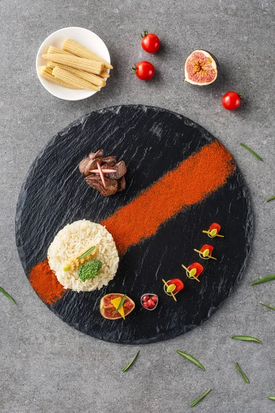 Vista superior de arroz, brócoli, higo y carne frita en plato negro con callos y tomates cherry - foto de stock